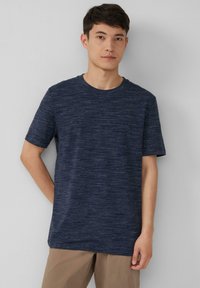 Marineblauwe T-shirt met korte mouwen, ronde hals, gemaakt van textuurstof met een gemêleerd patroon, gecombineerd met lichtbruin broek. Eenvoudig en casual ontwerp.