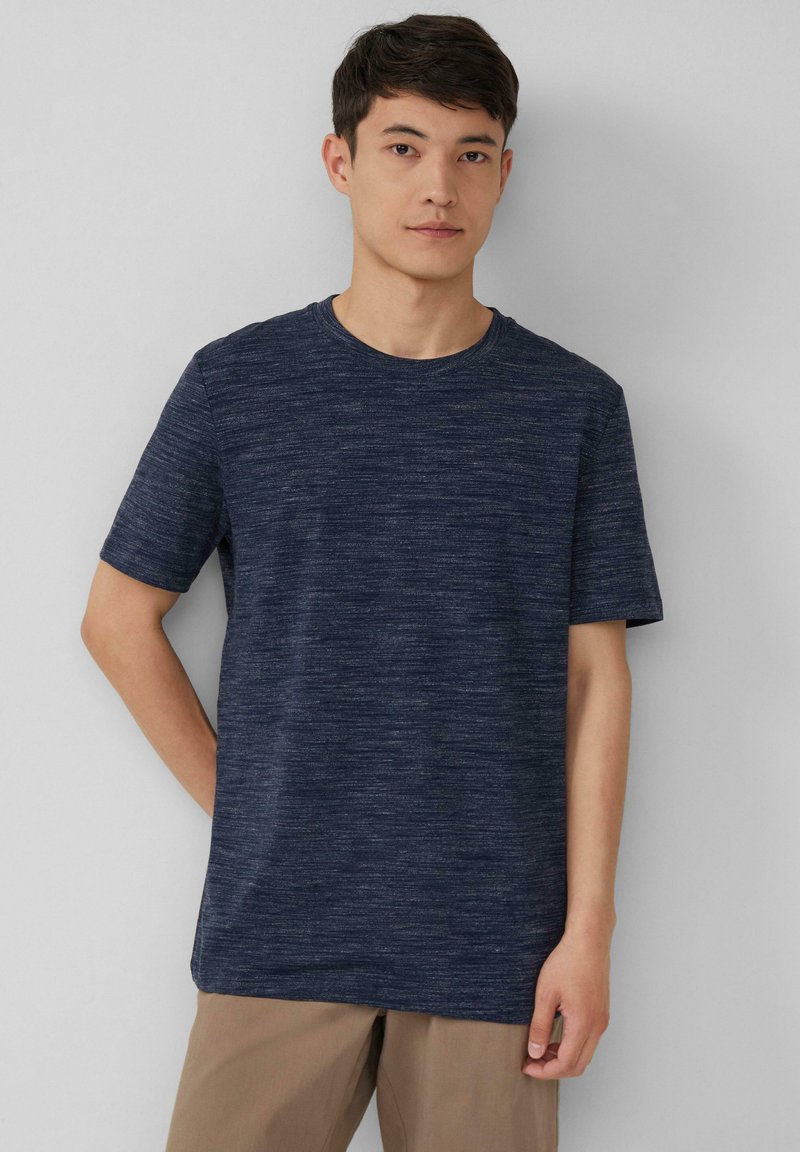 Marineblauwe T-shirt met korte mouwen, ronde hals, gemaakt van textuurstof met een gemêleerd patroon, gecombineerd met lichtbruin broek. Eenvoudig en casual ontwerp.