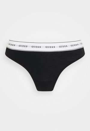 String nero realizzato in tessuto morbido, con una ampia fascia bianca in vita che presenta il marchio "GUESS" ripetuto in lettere nere.