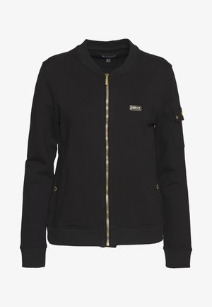 Black zip-up jacket made of soft material, featuring a ribbed collar and cuffs, gold zipper, and a small logo on the upper left side.