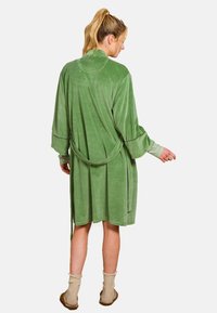 Groene velours badjas met lange mouwen, strikceintuur en een zachte textuur. Bereikt de middenkalfs met een relaxed fit en subtiele stikdetails.