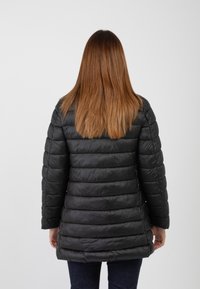 Parka nera imbottita con design a righe orizzontali, caratterizzata da maniche lunghe e un taglio di lunghezza media, realizzata in materiale leggero e lucido.