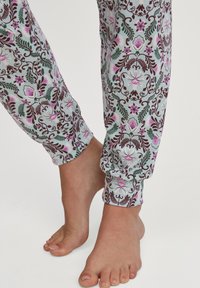 Geprinte katoenen pyjamabroek met een bloemenpatroon en bordeaux, groene en roze accenten. Enkellange boorden en lichtgewicht stof zichtbaar.