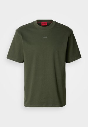 Camiseta de algodón de manga corta en verde oliva, con un cuello redondo y un logo sutil en gris en el pecho. Detalle del cuello interior en rojo.