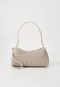 Beige handtas met textuur en een gebogen vorm, voorzien van een enkele bovenste handgreep en een afneembare crossbodyriem, geaccentueerd met gouden hardware.