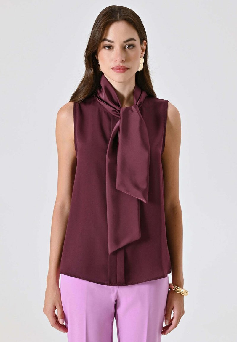 Blusa senza maniche color bordeaux con ampio colletto a fiocco realizzata in tessuto liscio; presenta un taglio dritto e un design minimalista.