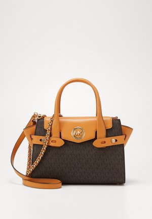 Sac à main en cuir marron et beige avec deux poignées supérieures, une bandoulière à chaîne et un logo MK rond doré sur le rabat avant.