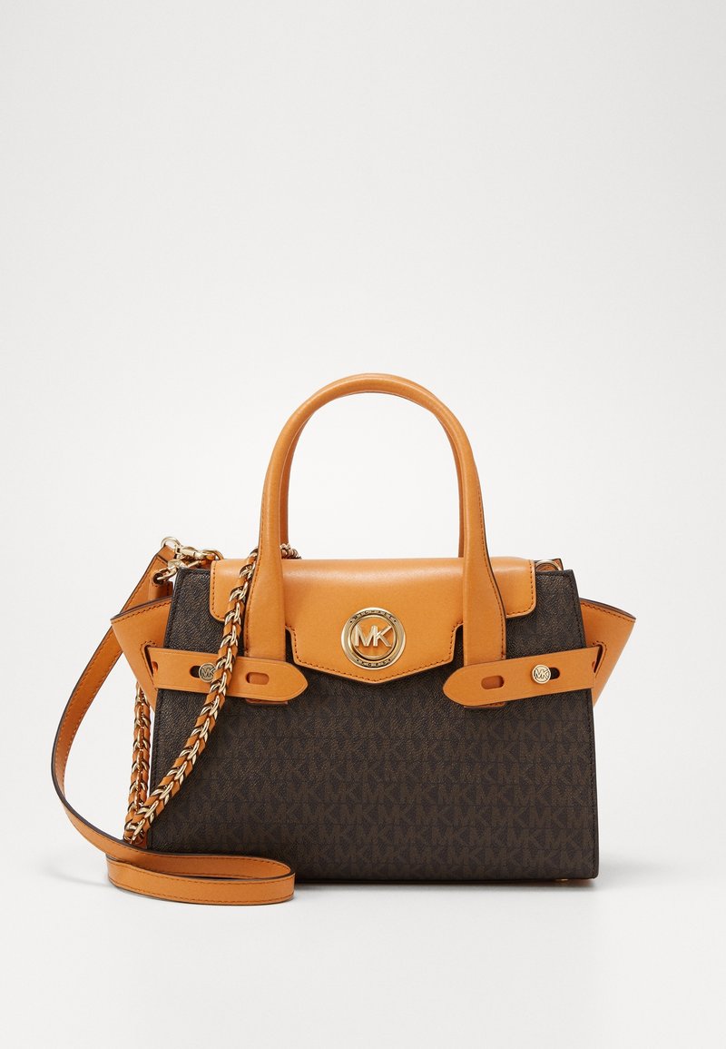Sac à main en cuir marron et beige avec deux poignées supérieures, une bandoulière à chaîne et un logo MK rond doré sur le rabat avant.