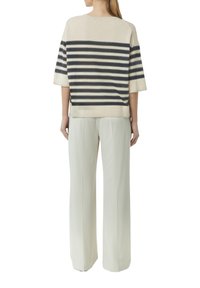 Beżowy sweter w paski z granatowymi poziomymi liniami, krótki rękaw i luźny fason, połączony z kremowymi spodniami z szerokimi nogawkami. Gładka tekstura.