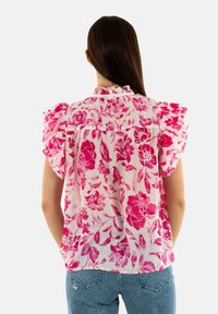 Blusa floral en tejido ligero con un patrón en rosa y blanco. Presenta mangas con volantes y un corte holgado, diseñada para la comodidad.