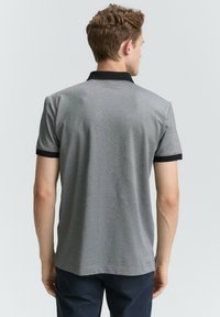 Grå kortærmet polo skjorte med sort krave og manchetter. Stoffet har en subtil tekstur og en klassisk pasform, der har en lige kant.