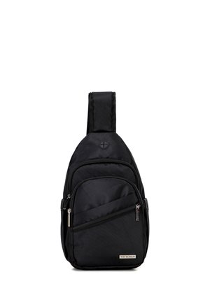 Schwarzer Sling-Rucksack mit einem breiten Schultergurt, mehreren Reißverschlussfächern und externem Kopfhöreranschluss, unten vorne mit dem Schriftzug Wittchen.