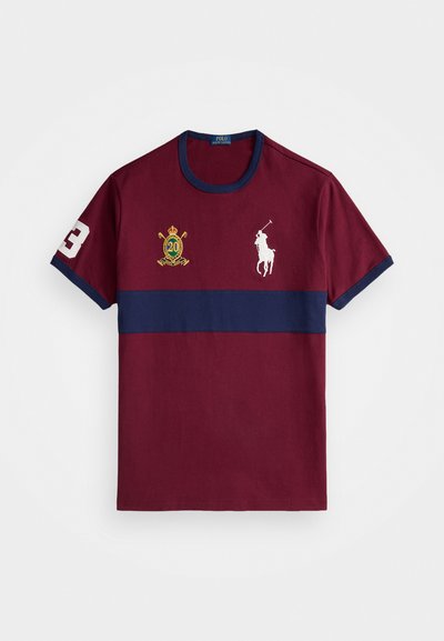 Mørkerød bomulls t-skjorte med en marineblå horisontal stripe, med hvite logoer inkludert en rytter og tallet 3, samt broderte detaljer.