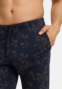 Marineblauwe pyjamabroek met een koordomhening, voorzien van een ingewikkeld bloemenpatroon in lichtblauw en bruin. Inclusief zijzakken en een knoopdetail.