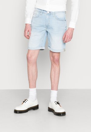 Lichtblauwe denimshorts met opgerolde zoom, gecombineerd met witte schoenen en sokken. Heeft een klassiek vijf-pocketontwerp en subtiele vervaging.