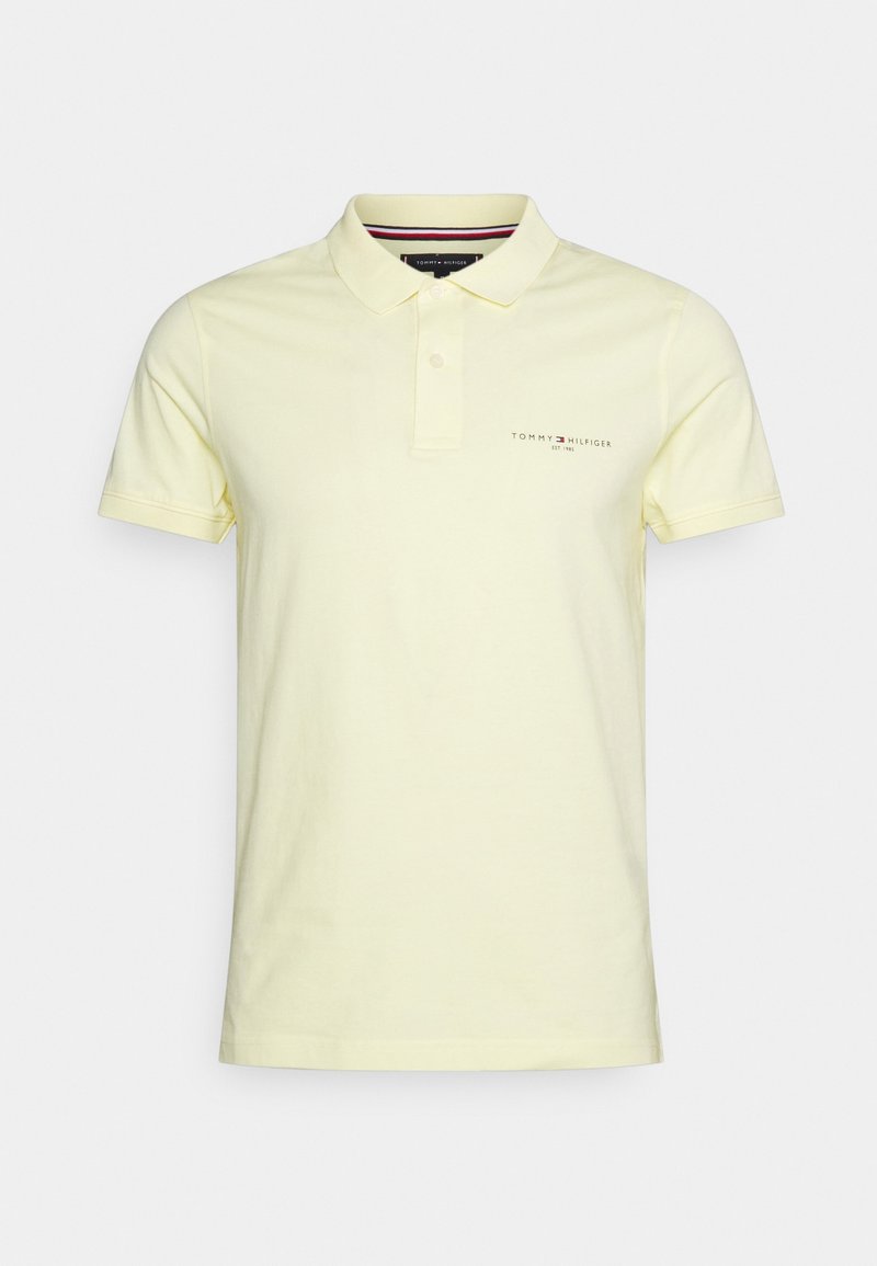 Polo manches courtes jaune pâle avec patte de boutonnage à deux boutons et petit logo Tommy Hilfiger sur la poitrine gauche.