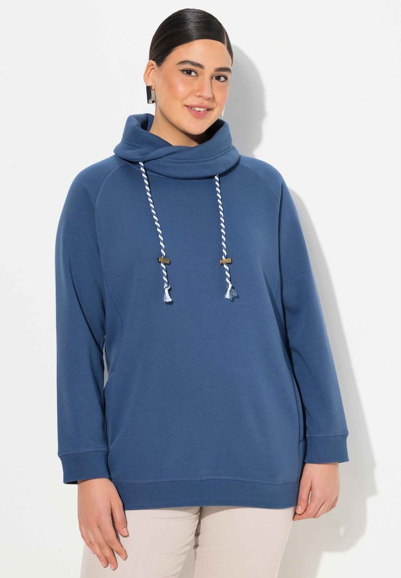 Felpa blu con collo a cappuccio e maniche lunghe, dotata di chiusura con doppio laccetto e frange, e polsini e orlo a costine. Tessuto morbido al tatto.