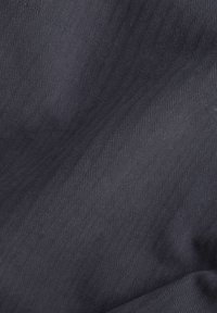 Marinblått tyg med ett diagonalt fiskbensmönster, mjuk textur och subtil glans, lämpligt för kläder eller möbelklädsel.