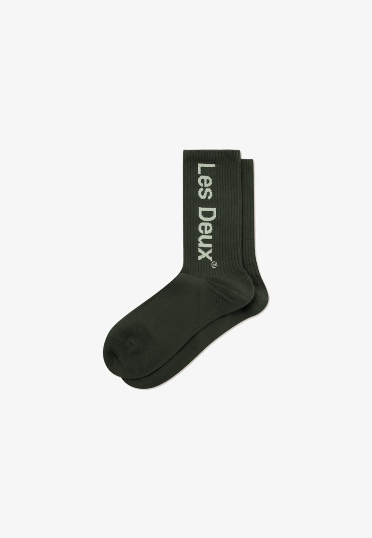 Calze a coste di un verde scuro con un logo che recita "Les Deux" in verde chiaro, caratterizzate da una texture morbida e una lunghezza standard.