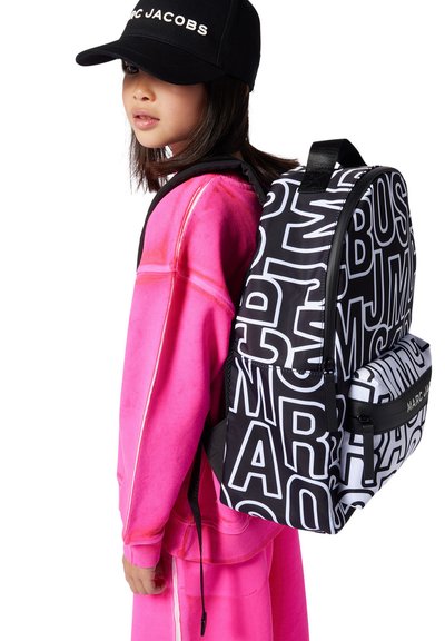 Zaino bianco e nero con tipografia audace, dotato di tasca con zip, spallacci regolabili e accento di logo a contrasto. Completo di colore rosa brillante.