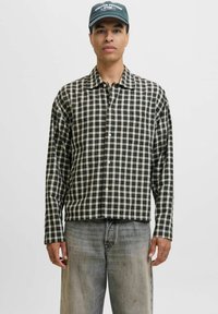 Schwarz-weißer karierter Langarmhemd mit Kragen, Knopfleiste und Manschetten, getragen mit hellgrauen, locker sitzenden Jeans.