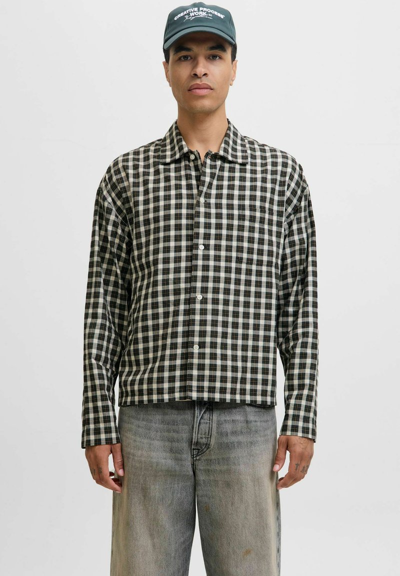 Schwarz-weißer karierter Langarmhemd mit Kragen, Knopfleiste und Manschetten, getragen mit hellgrauen, locker sitzenden Jeans.