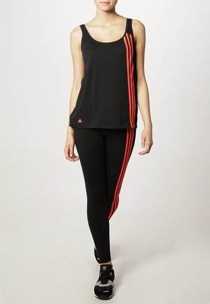 Canotta sportiva nera con strisce rosse, abbinata a leggins neri con strisce rosse sui lati. L'outfit è realizzato in materiale leggero e elasticizzato.