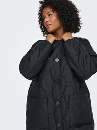 Melna kapitonēta jaka ar apaļu rakstu, ar pogu aizdari un divām priekšējām kabatām. Mīksta tekstūra un brīvs piegriezums.