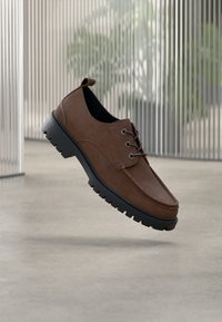 Smeđe cipele od brušene kože s vezicama, elegantnog dizajna, crnim gumenim potplatom i zaobljenim vrhom, s diskretnim šavovima i petljom na peti.