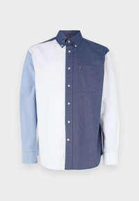 Chemise à boutons avec un design coloré en blocs, composée de sections bleu clair, blanc et bleu marine ; comprend une poche sur le côté droit.