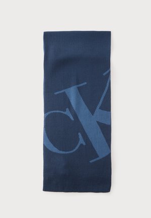 Dunkelblauer rechteckiger Strickschal mit großen hellblauen teilweise sichtbaren Buchstaben darauf, flach auf einem weißen Hintergrund ausgelegt.