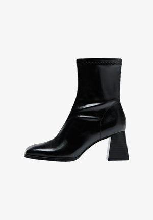 Schwarze Knöchelstiefel aus glattem Leder. Besitzen einen Blockabsatz mit einem strukturierten, gerippten Muster und einem schlanken, spitz zulaufenden Zehendesign.