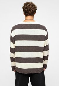 Gestreepte sweater met afwisselend bruine en crème kleuren, textuurstof, losse pasvorm, ronde halslijn en licht rafelige randen.
