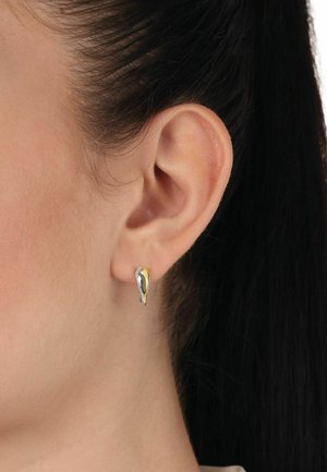 Gold- und silberne tropfenförmige Ohrstecker, glatte Oberfläche, polierte Verarbeitung, am Ohr eines Models montiert, zeigt elegantes Design und Farbkontrast.