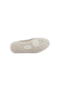 Beige instapschoen met een gestructureerde stof bovenkant en een flexibele witte rubberen zool met een zigzagpatroon en een cirkelvormige logo-detail.