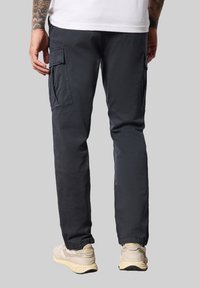 Pantalones cargo de color gris oscuro con bolsillos laterales, diseño de pierna recta y una textura suave. Combinados con zapatillas de color claro.