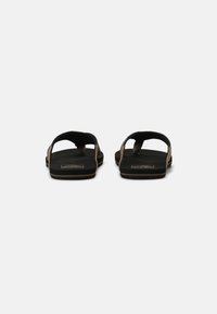 Black flip-flops with a textured strap and padded footbed, featuring a simple design and a sturdy sole for comfort and durability.