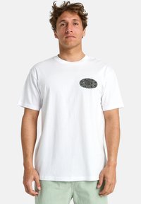Hvid bomulds T-shirt med et sort oval grafisk motiv med intrikate detaljer på venstre brystområde. Korte ærmer og klassisk pasform.