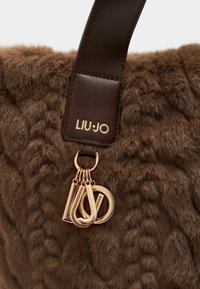 Borsa a tracolla in pelliccia marrone testurizzata con tracolla in pelle scura e charm in tonalità oro con le lettere "L", "J" e "O" attaccate alla tracolla.