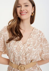 Šaty s krátkým rukávem s květinovým vzorem v béžové a krémové barvě, se špičatým výstřihem a tkaným páskem s kulatou přezkou.