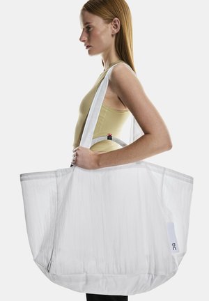 Weiße Stofftragetasche mit strukturierter Oberfläche, breiten Trägern und einem runden Handgriffen. Großes, geräumiges Design mit minimalistischen Details.