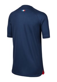 Camisa deportiva azul marino con cuello redondo, mangas cortas y un acento rojo en la parte inferior; incluye un pequeño detalle de la bandera francesa en la parte posterior.