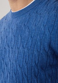 Suéter azul de punto trenzado con cuello redondo y puños acanalados. La tela tiene una textura suave con un patrón en relieve.