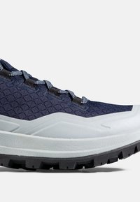 Marineblauer Wanderschuh mit strukturiertem Stoffobermaterial, hellgrauer verstärkter Zwischensohle, schwarzer Profilsohle und blau-grauen Schnürsenkeln.