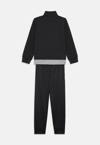 Zwarte sportieve tweedelige set bestaande uit een langmouw zip-up jas met een grijze zoom en bijpassende broek met boorden bij de enkels.