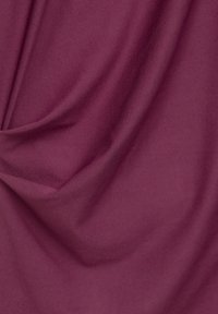 Tissu bordeaux avec une texture lisse, présentant des drapés doux et des plis délicats, indiquant un matériau léger et flexible.