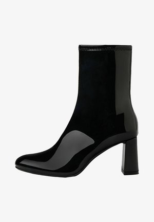 Bottine noire avec un design épuré, fabriquée avec des matériaux brillants et mats, présentant un bout pointu et un talon bloc. Texture lisse.