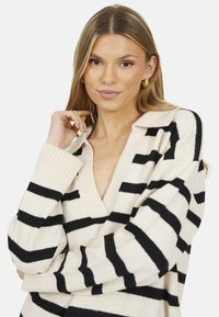 Maglione a maglia con scollo a V profondo, caratterizzato da righe orizzontali nere e crema, polsini a costine e una texture morbida.