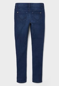 Jeans de mezclilla azul oscuro con un diseño ajustado, que cuentan con dos bolsillos traseros y detalles en hardware dorado. Textura suave, sin patrones adicionales.