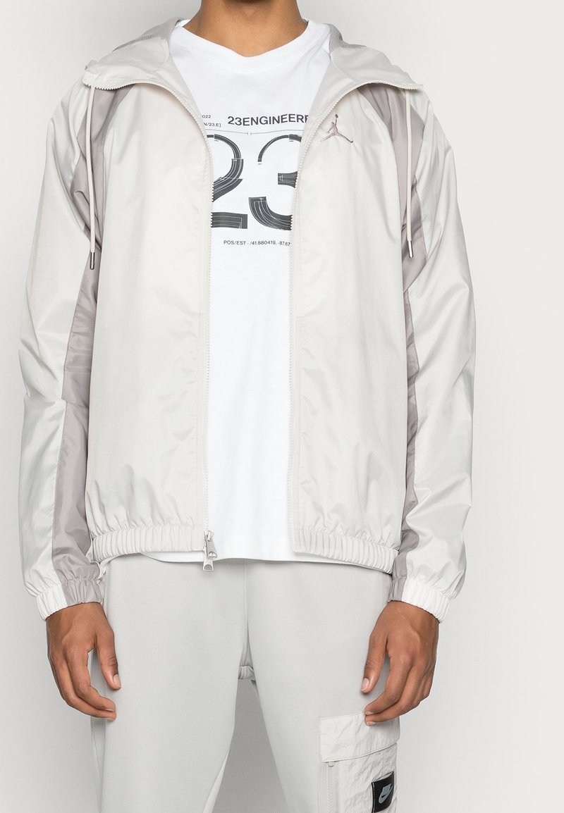 Lättvikts jacka med zip i off-white med grå detaljer. Har elastiska ärmslut och nederkant, med en minimalistisk design och Jordan-logotyp.